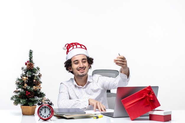 Satisfait de jeune homme d'affaires avec chapeau de père Noël drôle vérifiant les notes d'écriture et célébrer Noël au bureau sur fond blanc