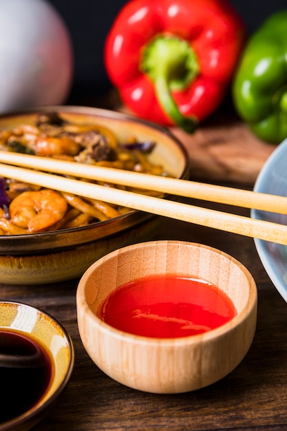 Photo gratuite sauce au piment fort dans un bol en bois avec des nouilles udon aux crevettes sur une table en bois