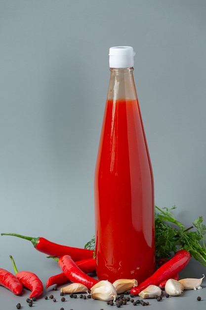Photo gratuite sauce chili en bouteille et poivrons sur une surface en bois sombre