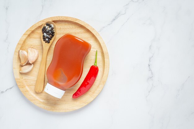 Sauce chili en bouteille et poivrons sur une surface en bois