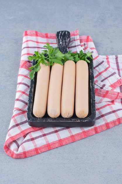 Photo gratuite saucisse bouillie fraîche sur une planche à découper noire.