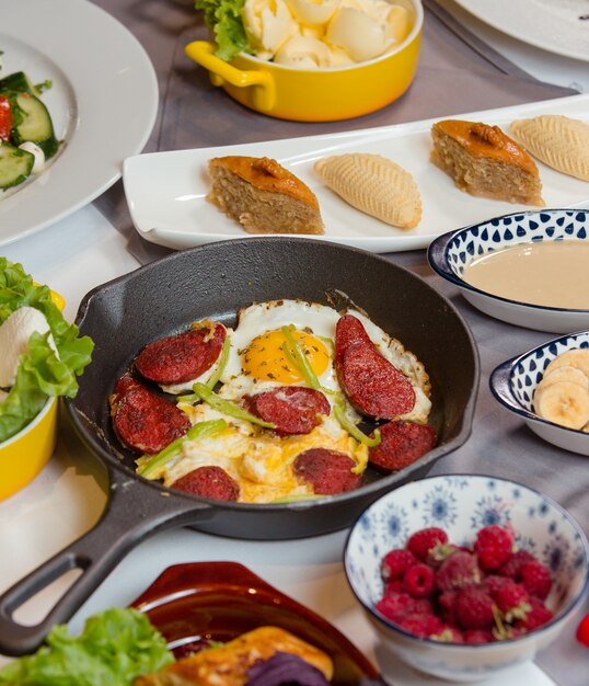 saucisse et œuf pour le petit déjeuner avec des bonbons, des fruits, des baies