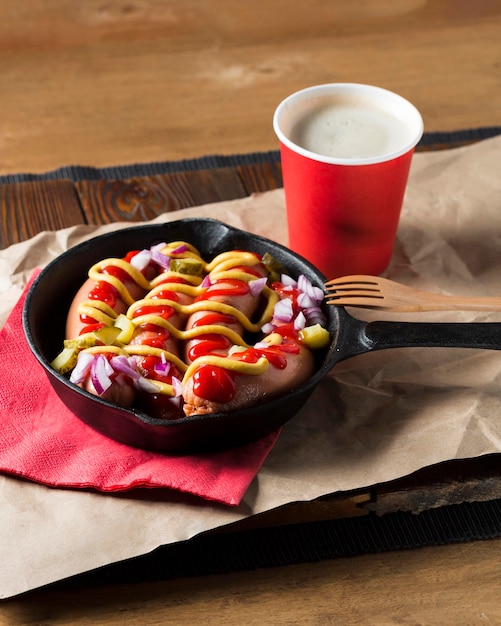 Saucisses à angle élevé dans une casserole avec des sauces et l'oignon