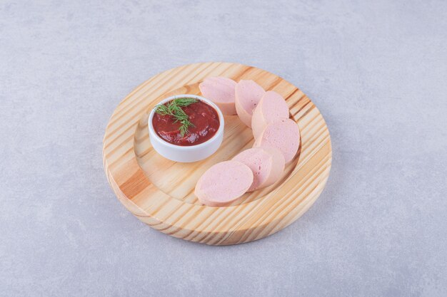 Saucisses bouillies et ketchup sur plaque de bois.