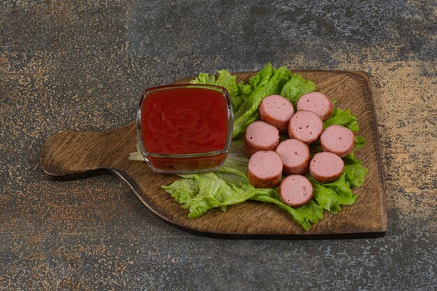 Saucisses frites et ketchup sur planche de bois.