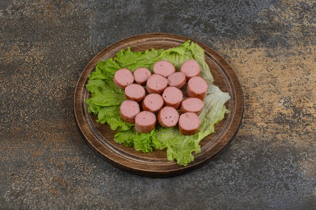 Saucisses frites tranchées sur planche de bois.