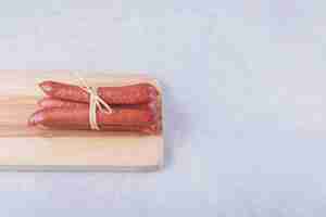 Photo gratuite saucisses fumées attachées avec une corde sur planche de bois.