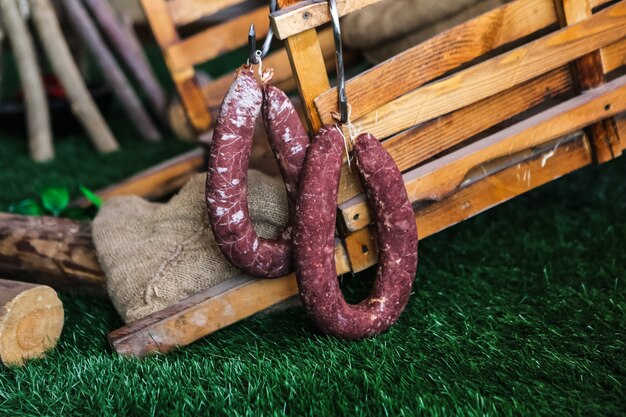 Saucisses fumées sur l'herbe avec des boîtes en bois sur vue latérale arrière