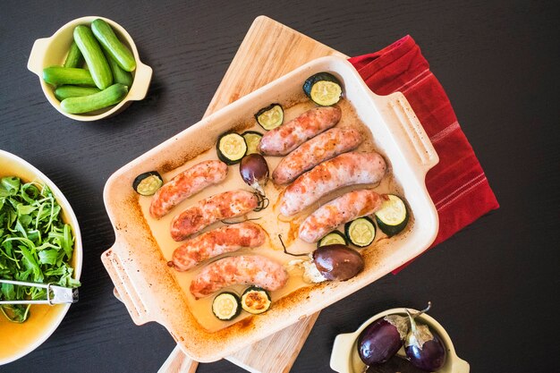 Saucisses juteuses aux légumes sur un plat allant au four