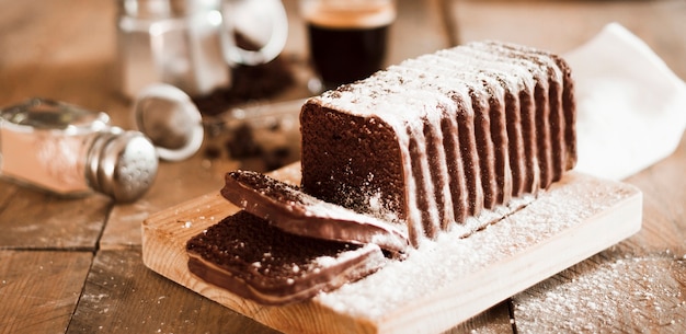 Saupoudrage de sucre sur une tranche de gâteau sur la planche à découper