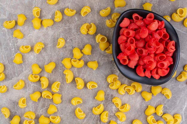 Saupoudré de pâtes crues et un bol de pâtes rouges, sur la surface en marbre