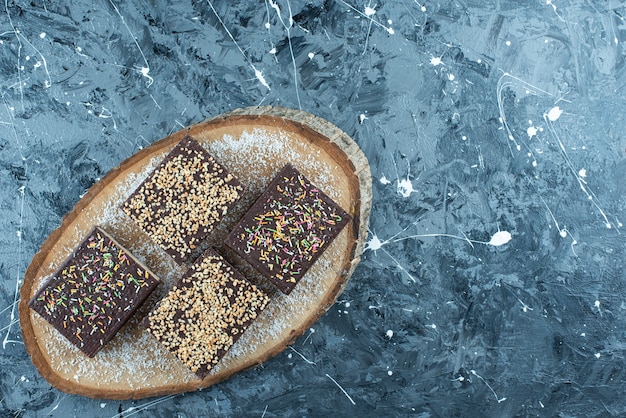 Saupoudrer de sucre sur une gaufre au chocolat sur une planche, sur la table bleue.