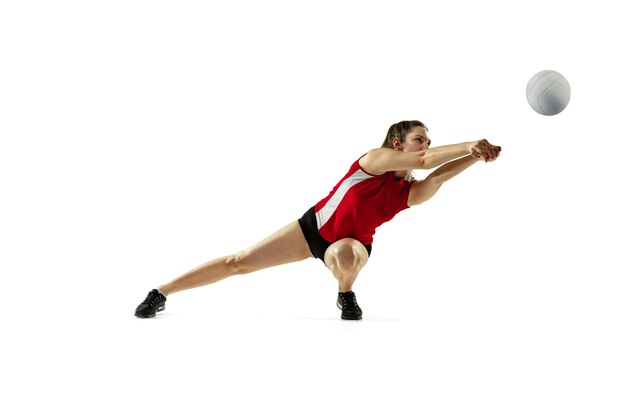 En saut et en vol. Jeune joueuse de volley-ball isolée sur un mur blanc. Femme en vêtements de sport et chaussures de sport, jouant. Concept de sport, mode de vie sain, mouvement et mouvement.