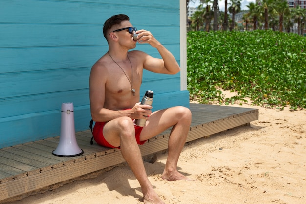 Photo gratuite sauveteur complet avec boisson sur la plage