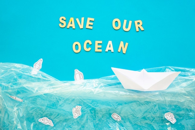 Photo gratuite sauvons nos mots de l'océan et bateau en papier