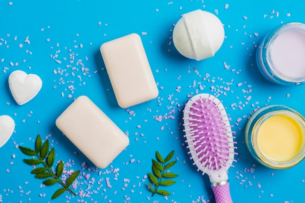 Photo gratuite savon; bombe de bain; crème hydratante et brosse à cheveux sur fond bleu