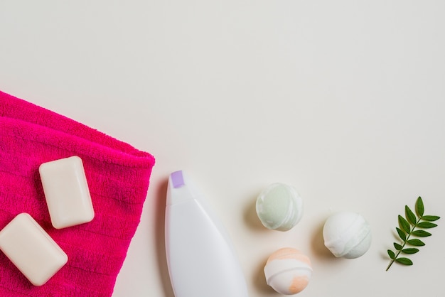 Savon; bombe de bain; serviette hydratante et rose avec des feuilles sur fond blanc