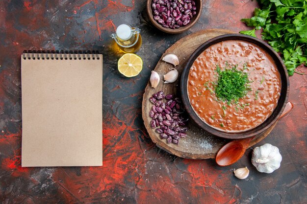 Savon tomate haricots ail cuillère sur planche à découper en bois et bouteille d'huile vert citron à côté de l'ordinateur portable