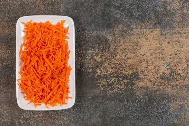 De savoureuses carottes en julienne sur plaque blanche.