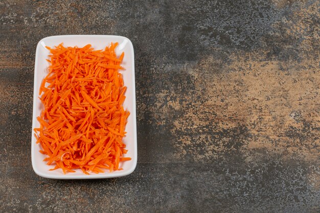 De savoureuses carottes en julienne sur plaque blanche.