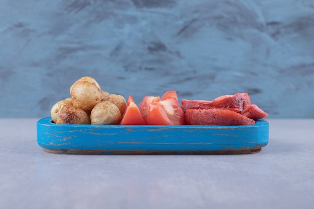 Savoureuses saucisses grillées et tomates sur plaque bleue.