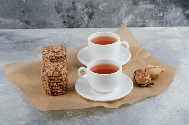 De savoureux biscuits aux graines et au chocolat avec une tasse de thé sur du marbre.