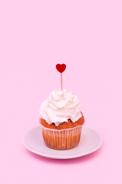 Savoureux gâteau avec fouet et ornement coeur sur baguette