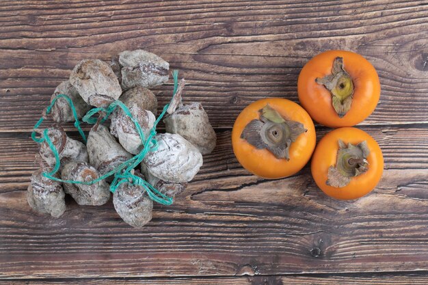 Savoureux kakis fuyu et kakis séchés sur une surface en bois