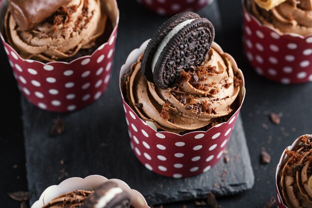 De savoureux petits gâteaux muffins au chocolat avec crème au beurre décorés dans des tasses. Fermer