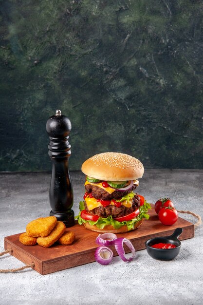 Savoureux sandwich fait maison et tomates pépites de poulet oignons poivre sur planche à découper en bois ketchup sur surface floue en vue verticale