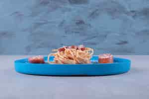 Photo gratuite de savoureux spaghettis aux saucisses sur plaque bleue.
