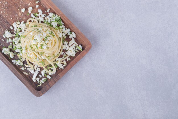 De savoureux spaghettis bouillis avec du fromage râpé sur une planche de bois.