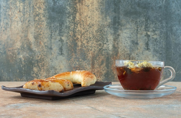 Savoureux thé à la camomille avec des biscuits sur table en marbre.