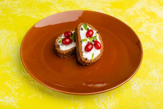 De savoureux toasts de pain avec de la crème sure et des cornouillers à l'intérieur de la plaque brune sur jaune