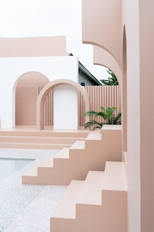 Scène d'espace vide minimal avec mur peint en rose, arc, escalier rose et cactus artificiel