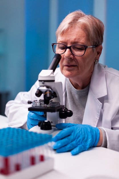 Scientifique principal regardant au microscope à l'échantillon dans le laboratoire de biologie