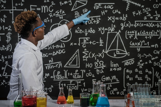 Les scientifiques portent des lunettes et indiquent des formules au tableau dans le laboratoire