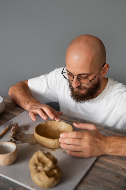 Photo gratuite sculpteur masculin travaillant avec de l'argile dans le studio