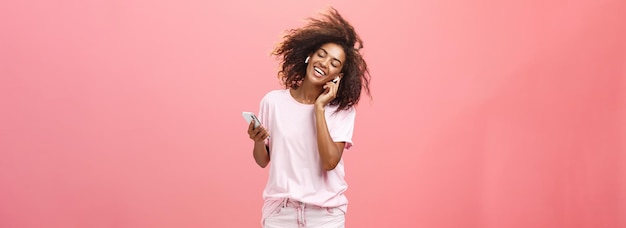 Photo gratuite se débarrasser de l'inquiétude avec de bonnes mélodies dans les oreilles satisfait attrayante jeune femme africaine à la mode