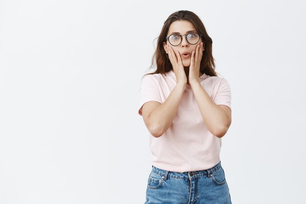 Se demande et amusé jeune brune avec des lunettes posant