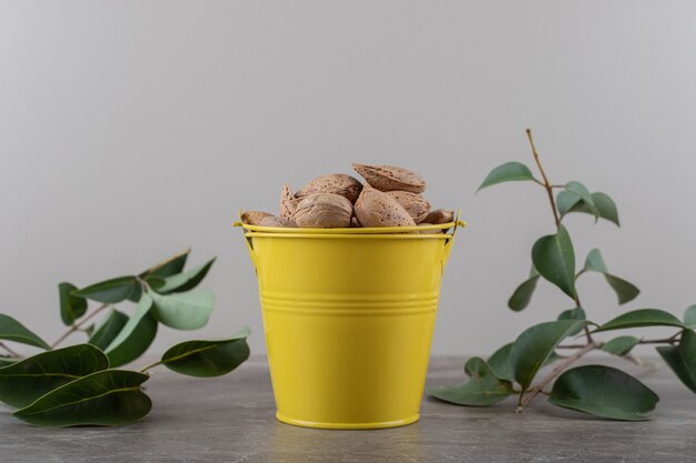 Un seau d'amandes et de feuilles sur la surface en marbre. sur la surface du marbre