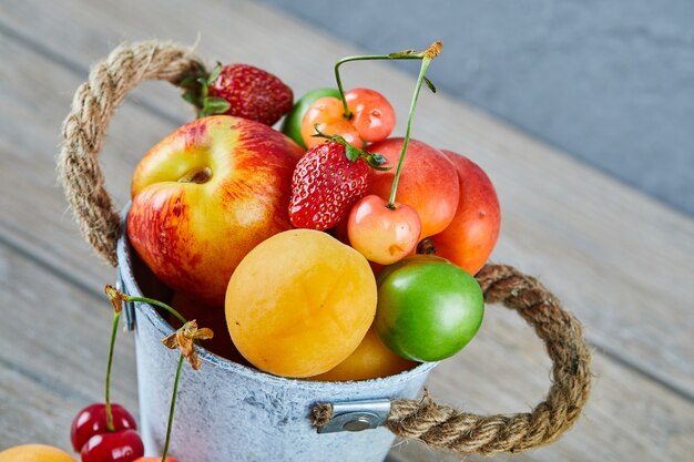 Seau de fruits frais d'été sur table en bois.