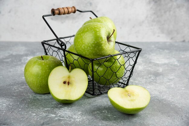 Seau en métal de pommes vertes fraîches sur table en marbre.