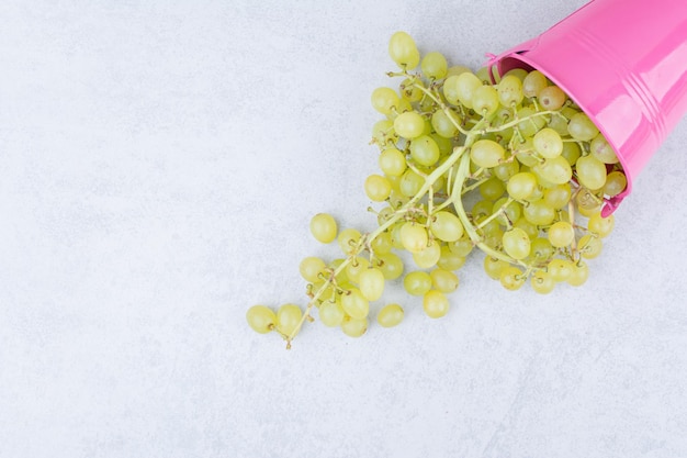 Un seau rose plein de raisins verts sucrés. photo de haute qualité