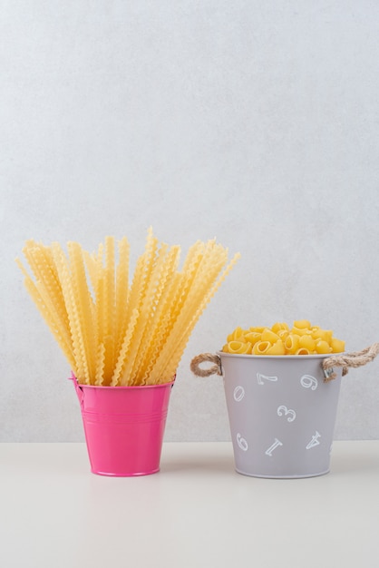 Photo gratuite seaux de pâtes crues mixtes sur surface blanche