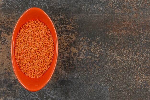 Photo gratuite sécher les lentilles rouges dans un bol orange.