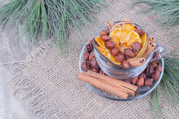 Sécher les tranches d'orange et les hanches avec de la cannelle dans une tasse en verre