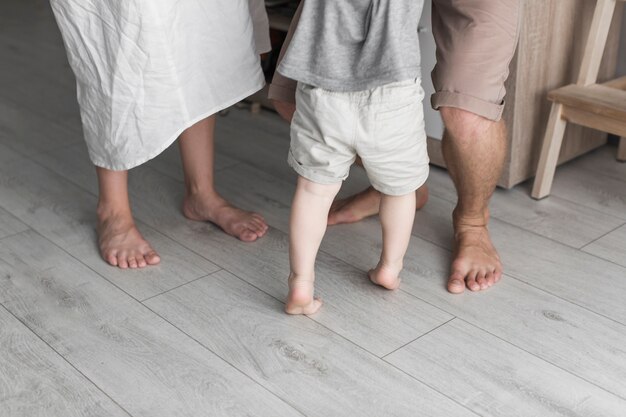 Section basse du parent avec son petit fils debout sur un plancher de bois franc