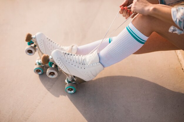 Section basse de la femme attachant de la dentelle de patin à roulettes