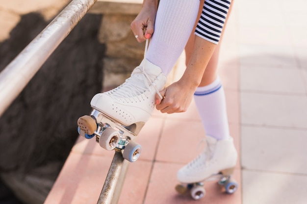 Photo gratuite section basse de la femme attachant la dentelle de patins à roulettes